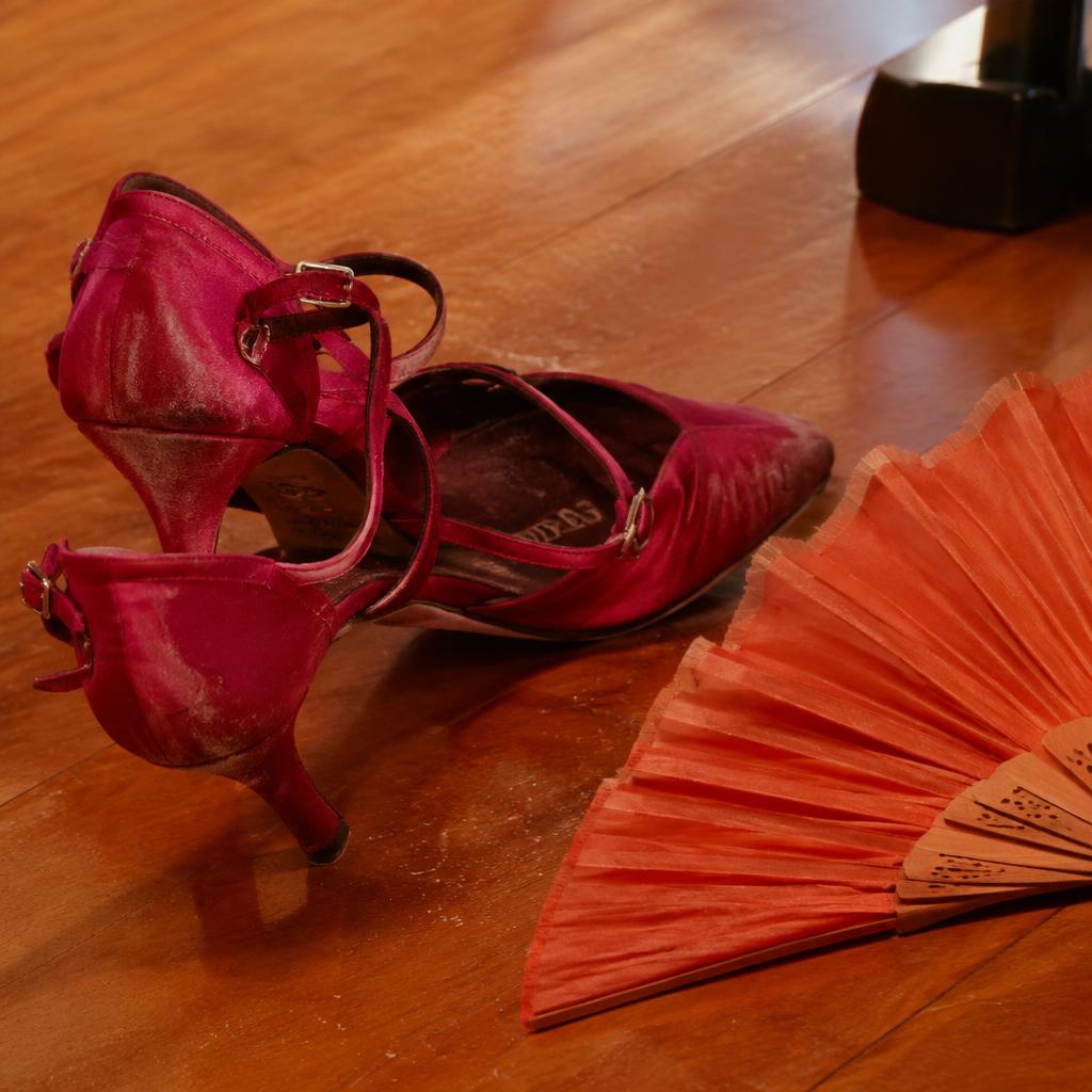 Zapatos de baile y abanico sobre piso de madera